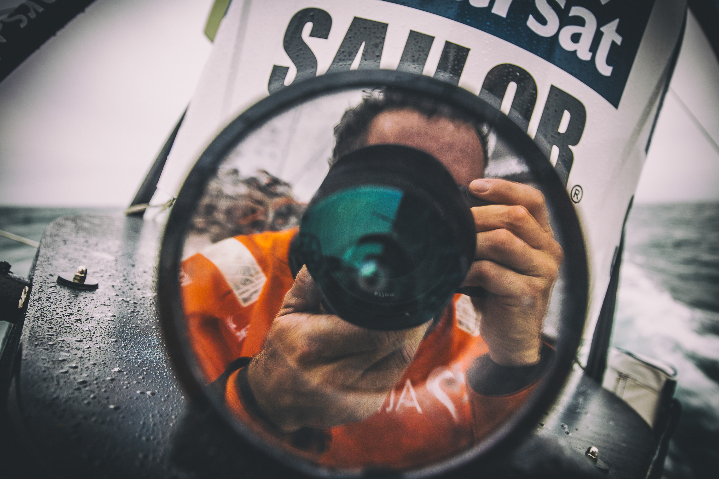 May 22, 2015. Leg 7 to Lisbon on board Team Alvimedica. Day 05. OBR Amory Ross' reflection on the stern camera lens. The drag race northeast towards the eastern edge of the ice exclusion zone continues with the front five all still within a few miles of each other.